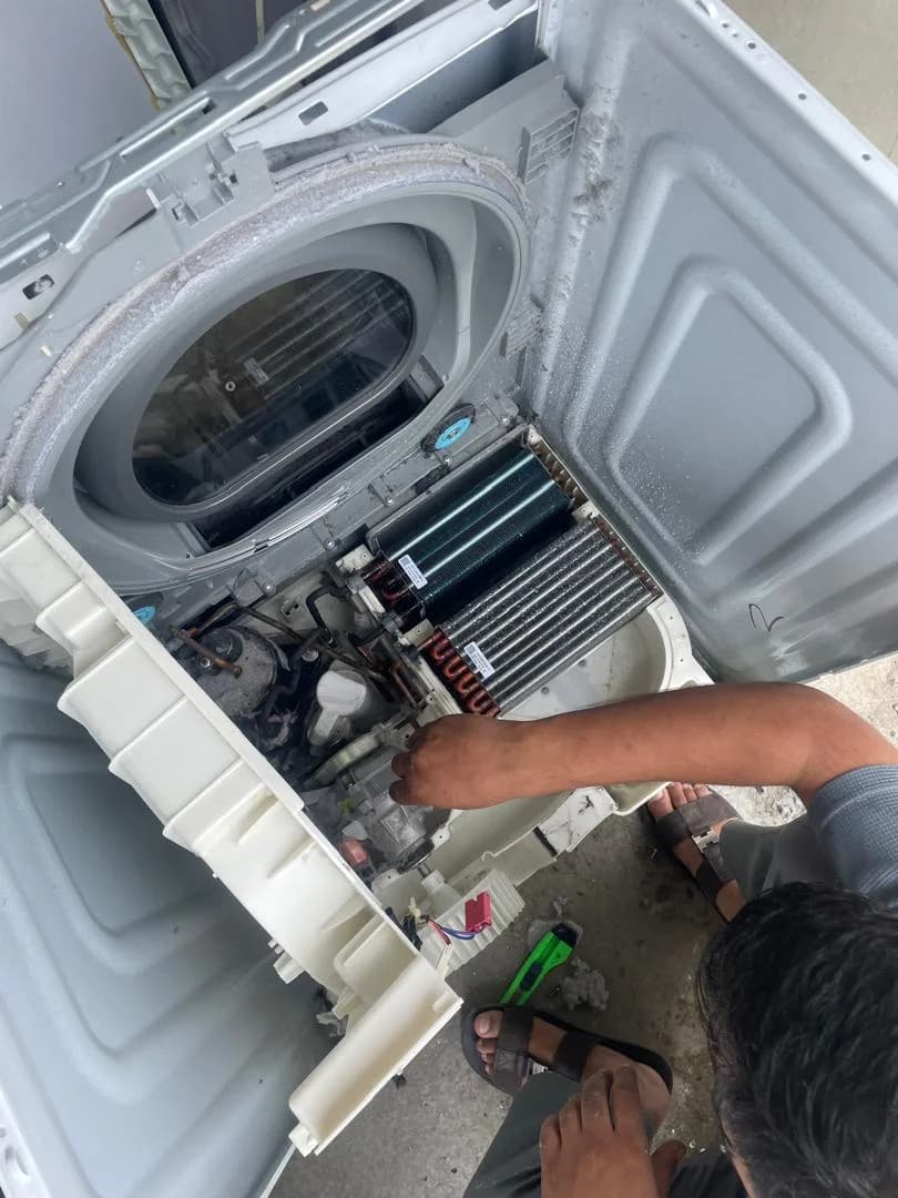 Technician working on the exposed components of a tumble dryer