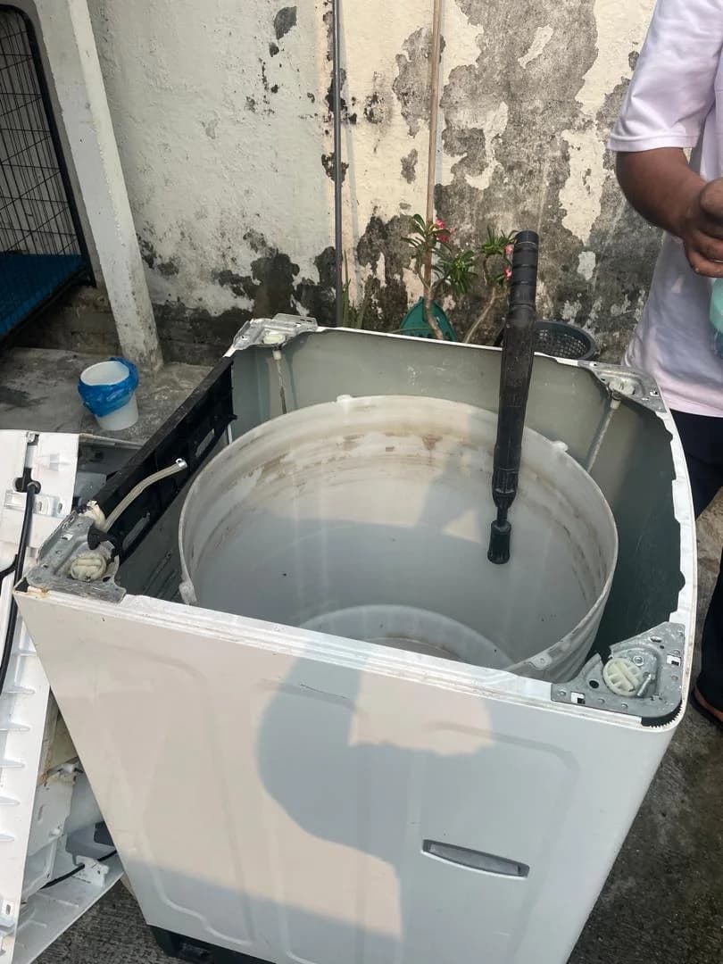 Top-load washing machine opened with its drum removed for servicing
