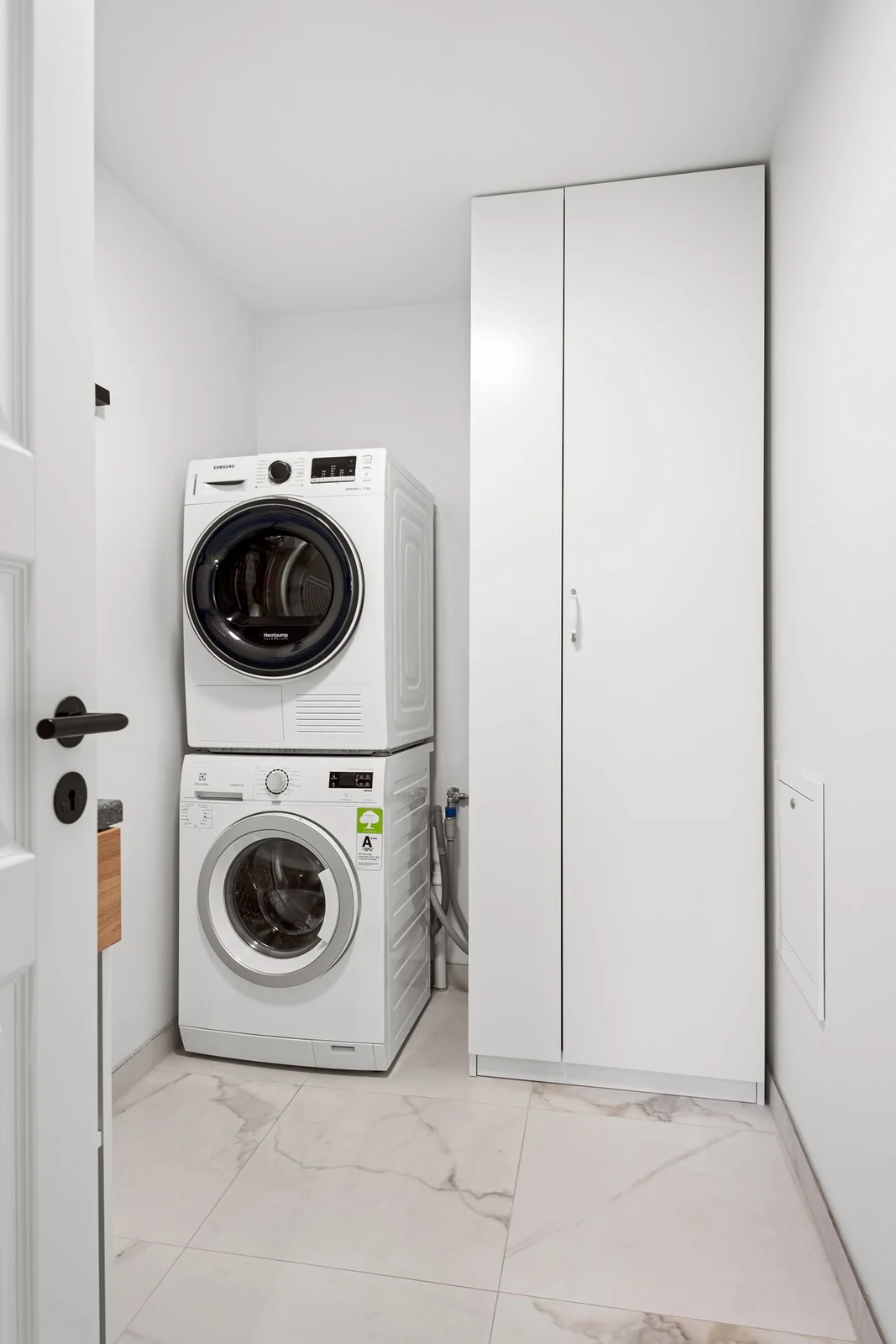 Stacked tumble dryer and washer in a minimalist laundry room